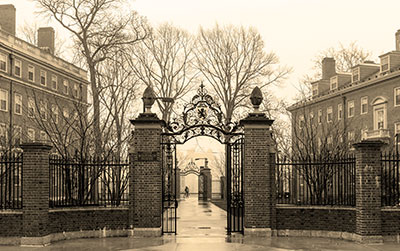 Sepia-toned photo of a gate leading into the campus of Harvard University