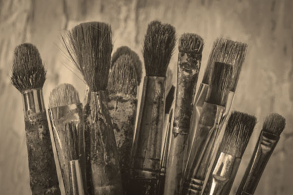 Closeup photograph of oil painting brushes in a jar