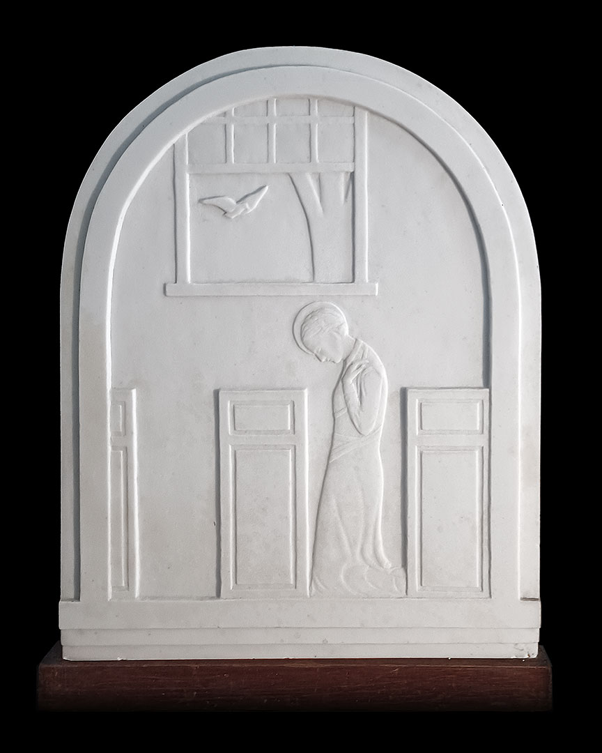 White bas relief of dove at the window above a kneeling Mary